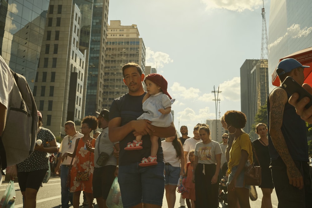 a group of people walking down a street next to tall buildings