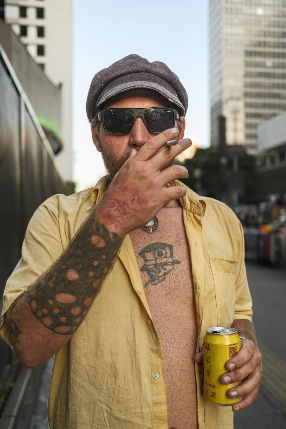 um homem fumando um cigarro e segurando uma lata de cerveja