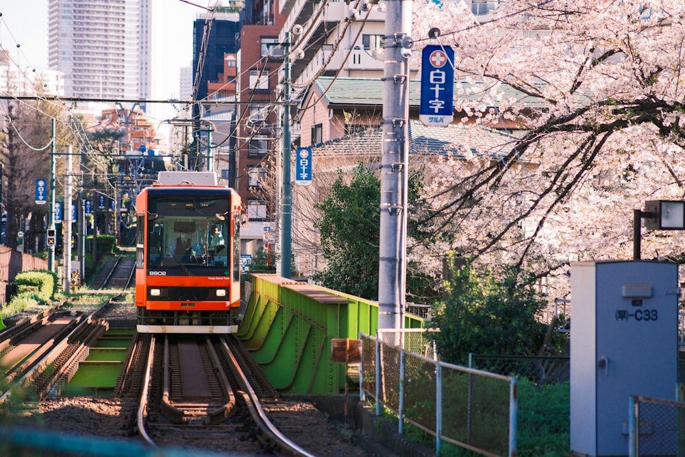 a red train traveling down train tracks next to tall buildings