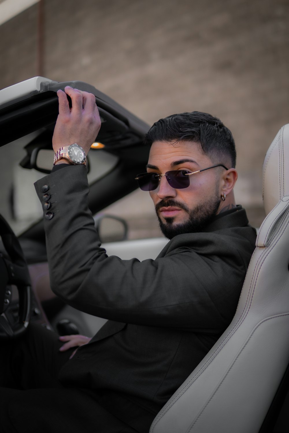 a man in a suit and sunglasses sitting in a car