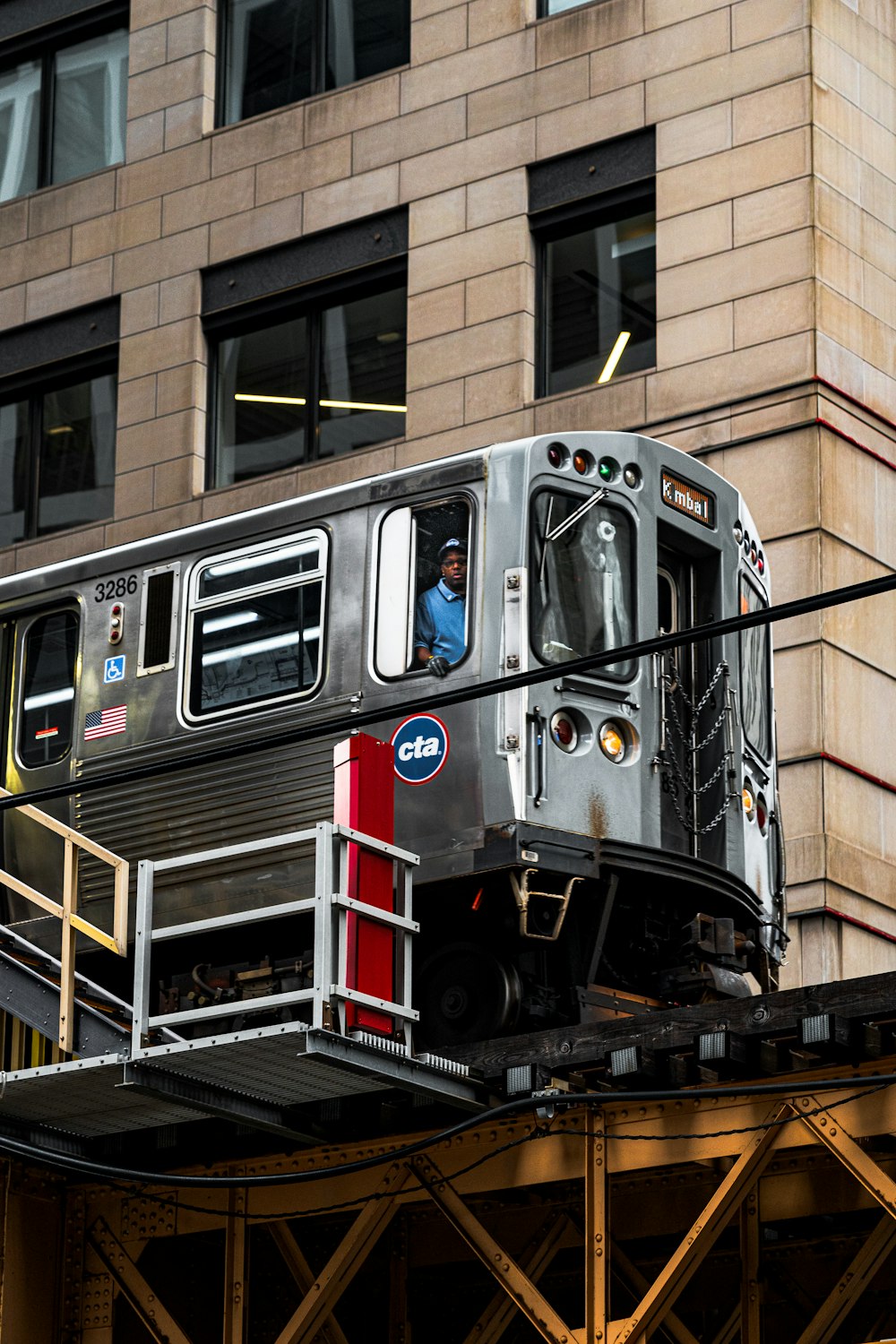 a silver train traveling down train tracks next to a tall building