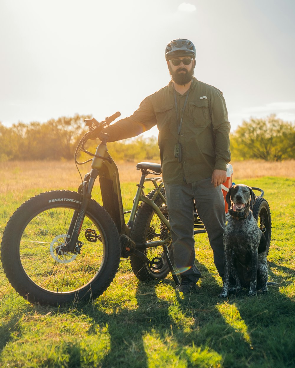 a man standing next to a bike and a dog