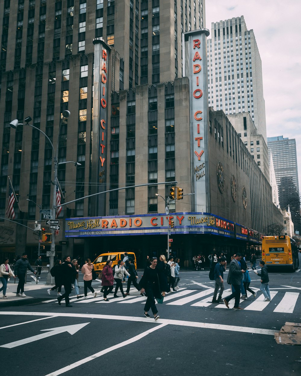 a crowd of people crossing a street in front of a theater