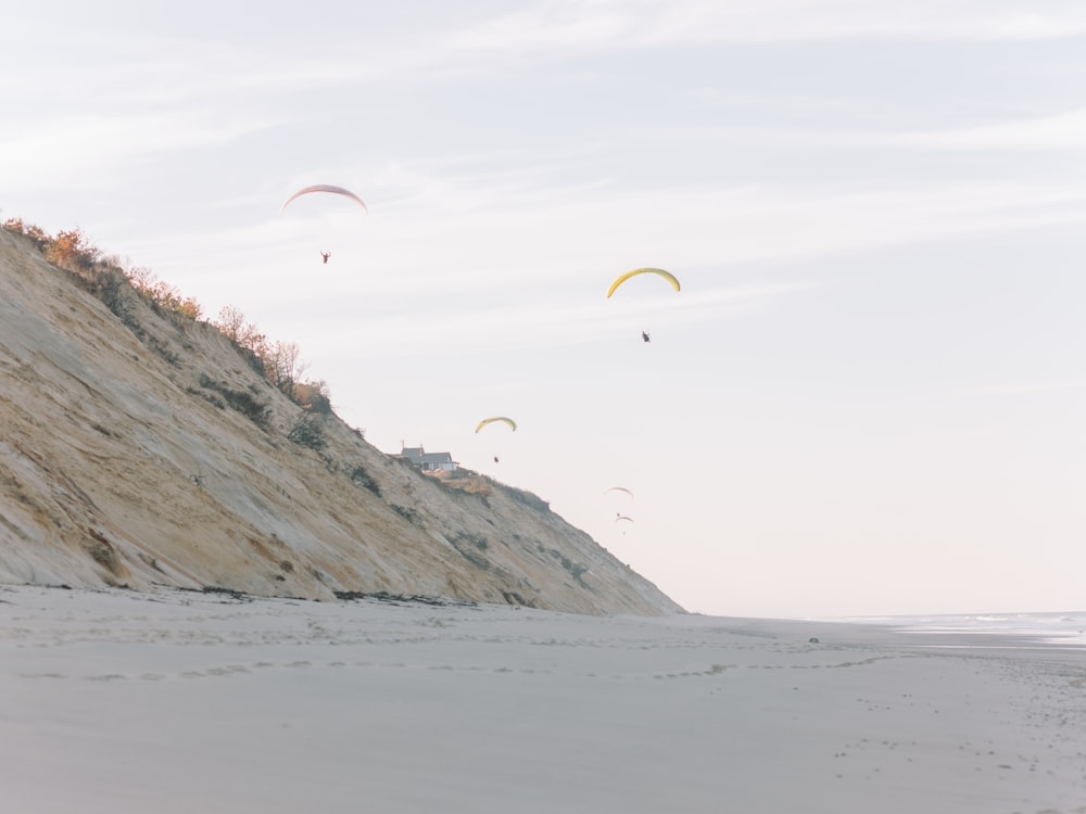 a group of people flying kites on top of a sandy beach