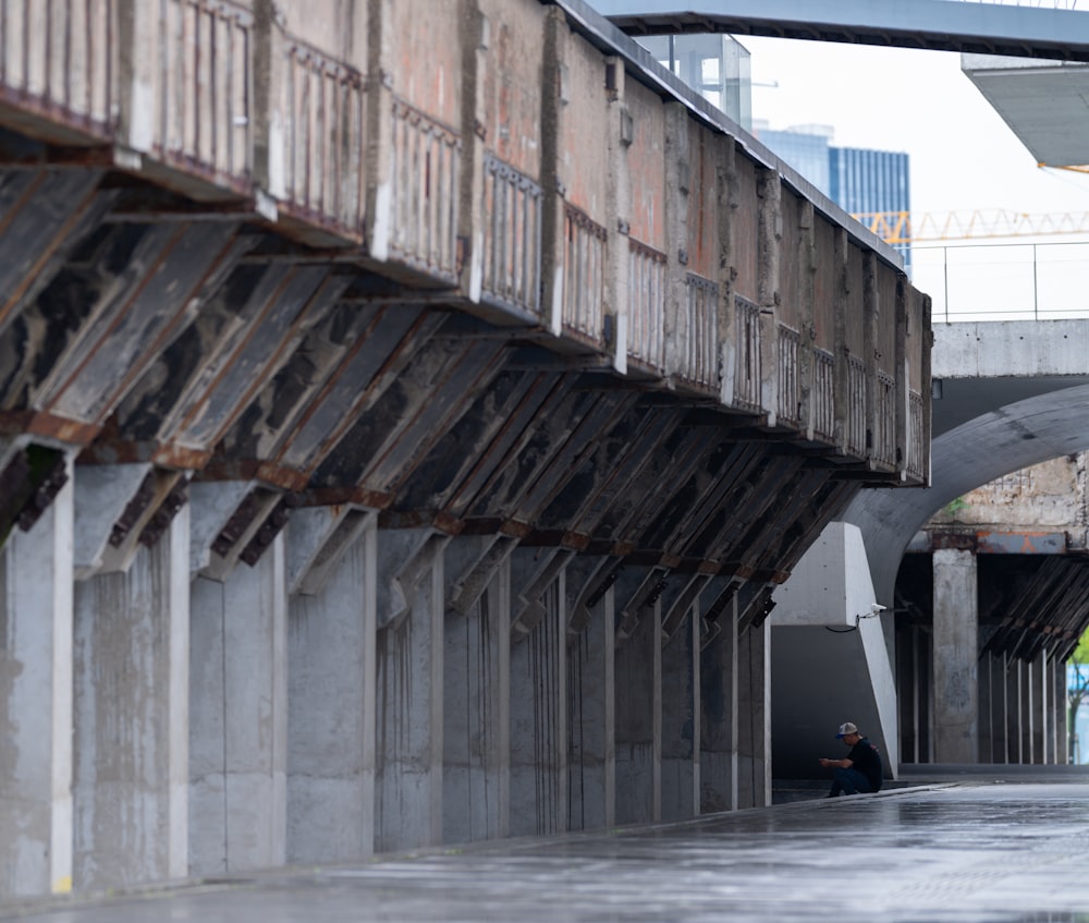 a man riding a skateboard down a street under a bridge