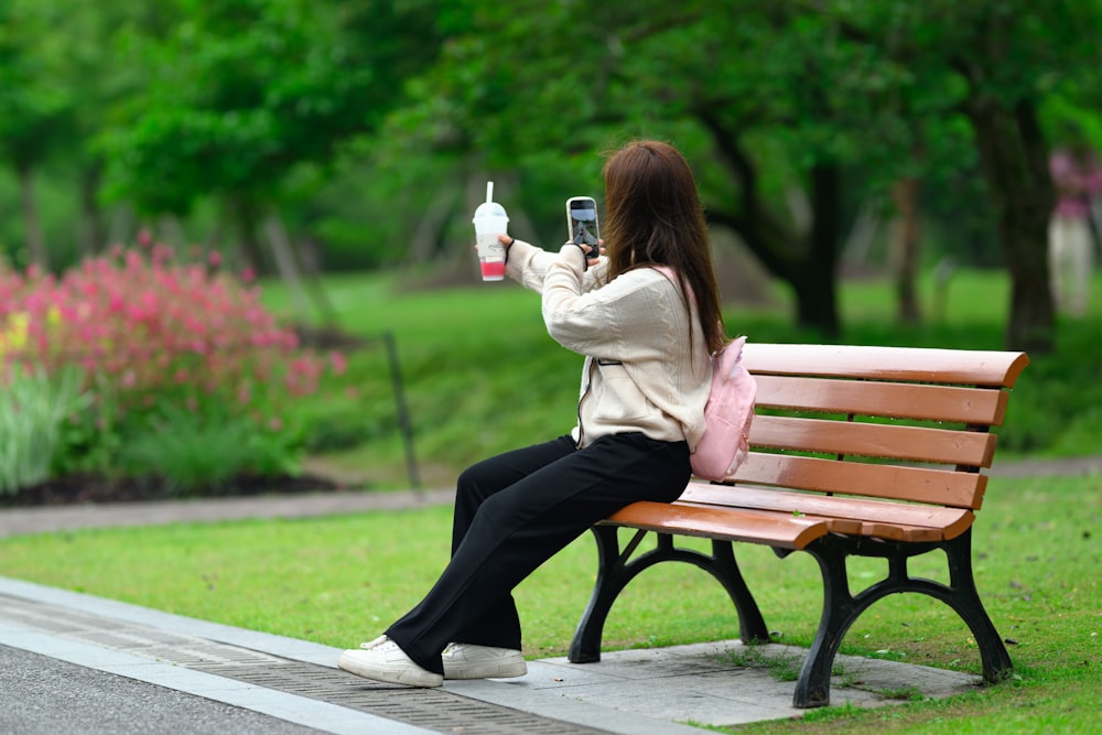 a woman sitting on a bench taking a picture with her cell phone