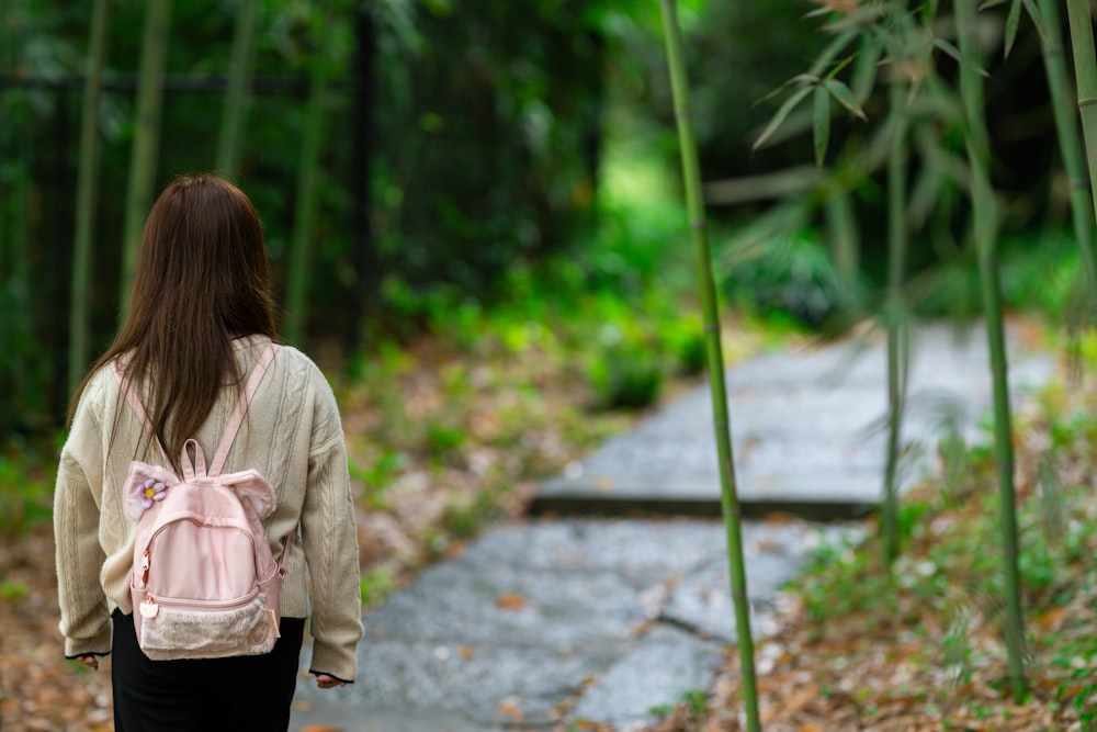 a woman with a pink backpack walking down a path