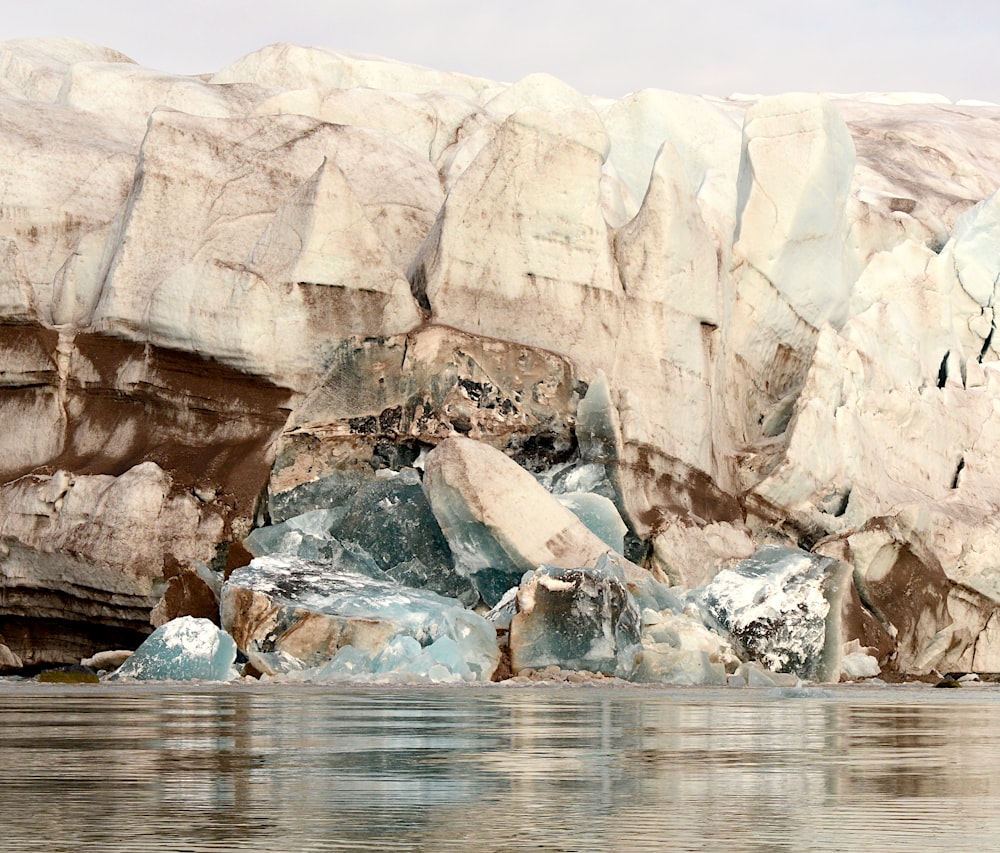 a group of large rocks sitting next to a body of water