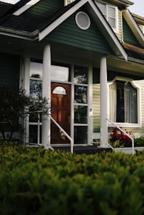 a green house with a red door and white pillars