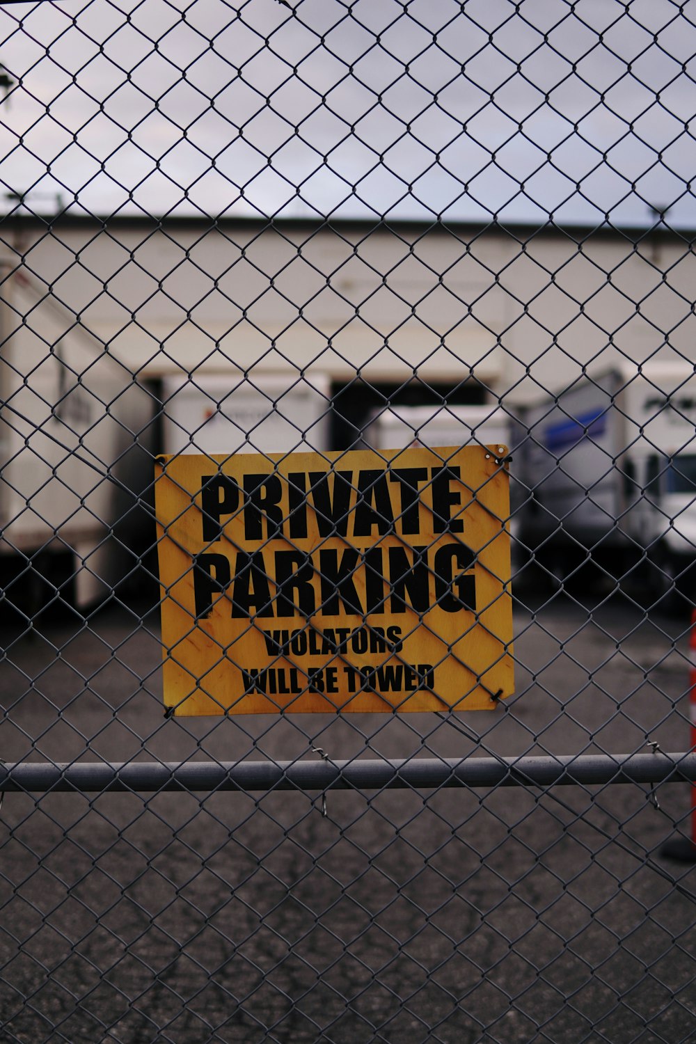 a private parking sign on a chain link fence
