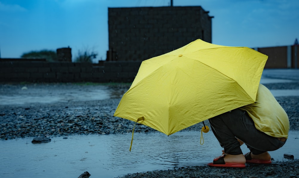 a person kneeling down with a yellow umbrella