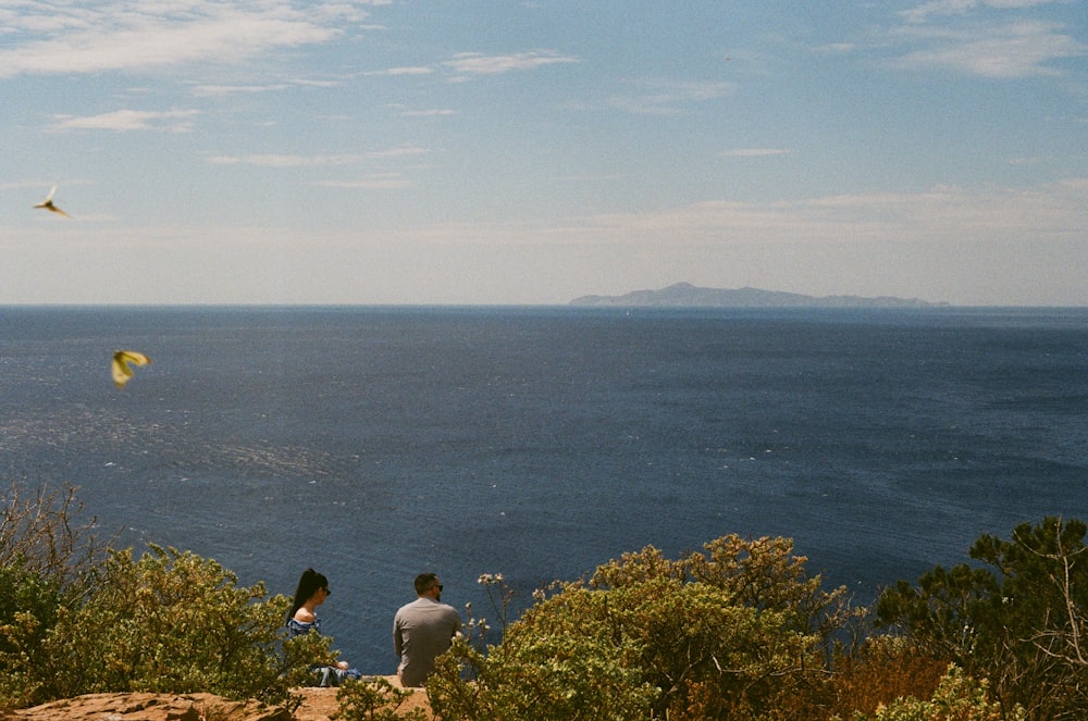 a couple of people standing on top of a cliff