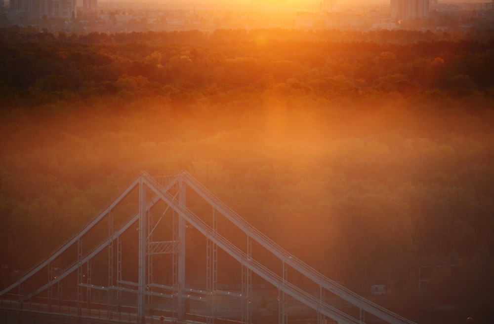 the sun is setting over a bridge in a foggy city