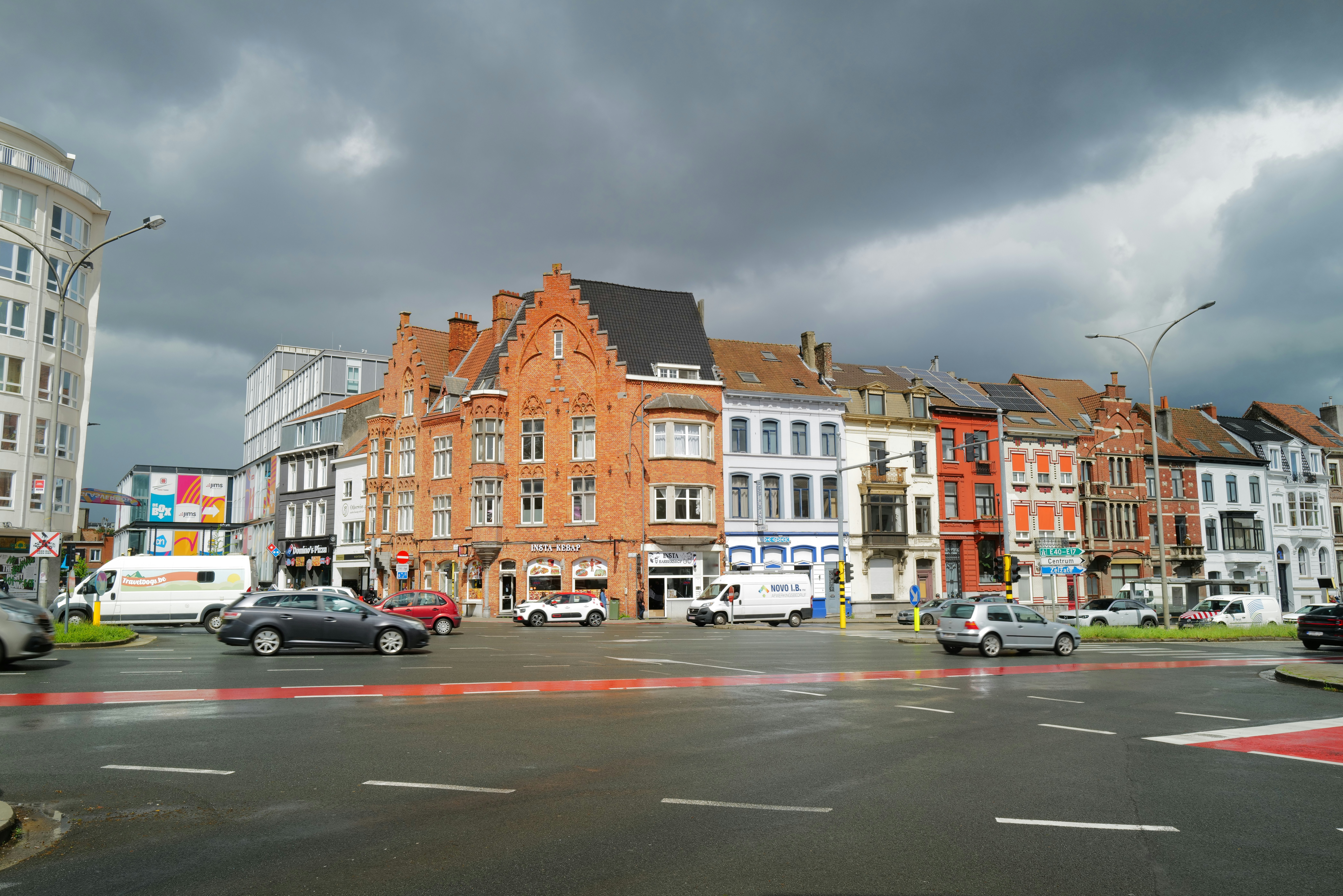 a group of cars driving down a street next to tall buildings
