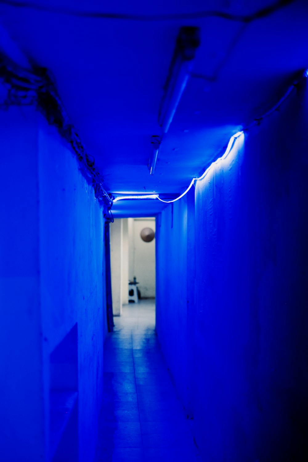 a long hallway with a blue light at the end of it