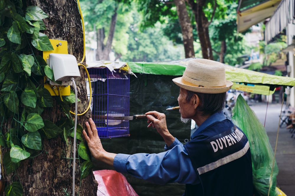 a man smoking a cigarette next to a tree