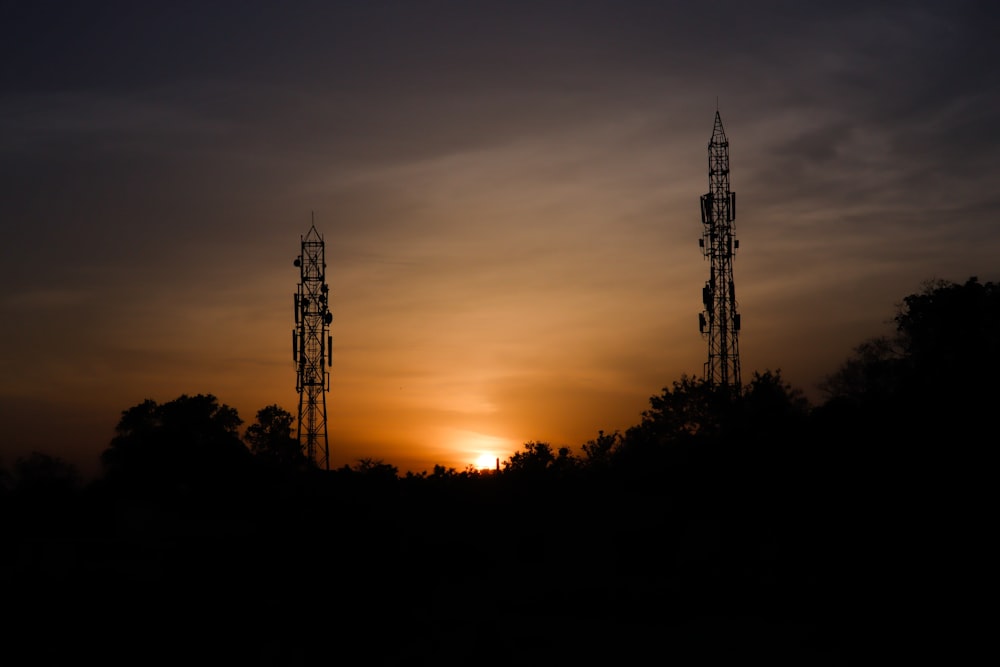 the sun is setting behind two cell towers