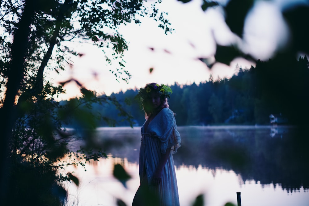 a woman standing next to a tree near a body of water