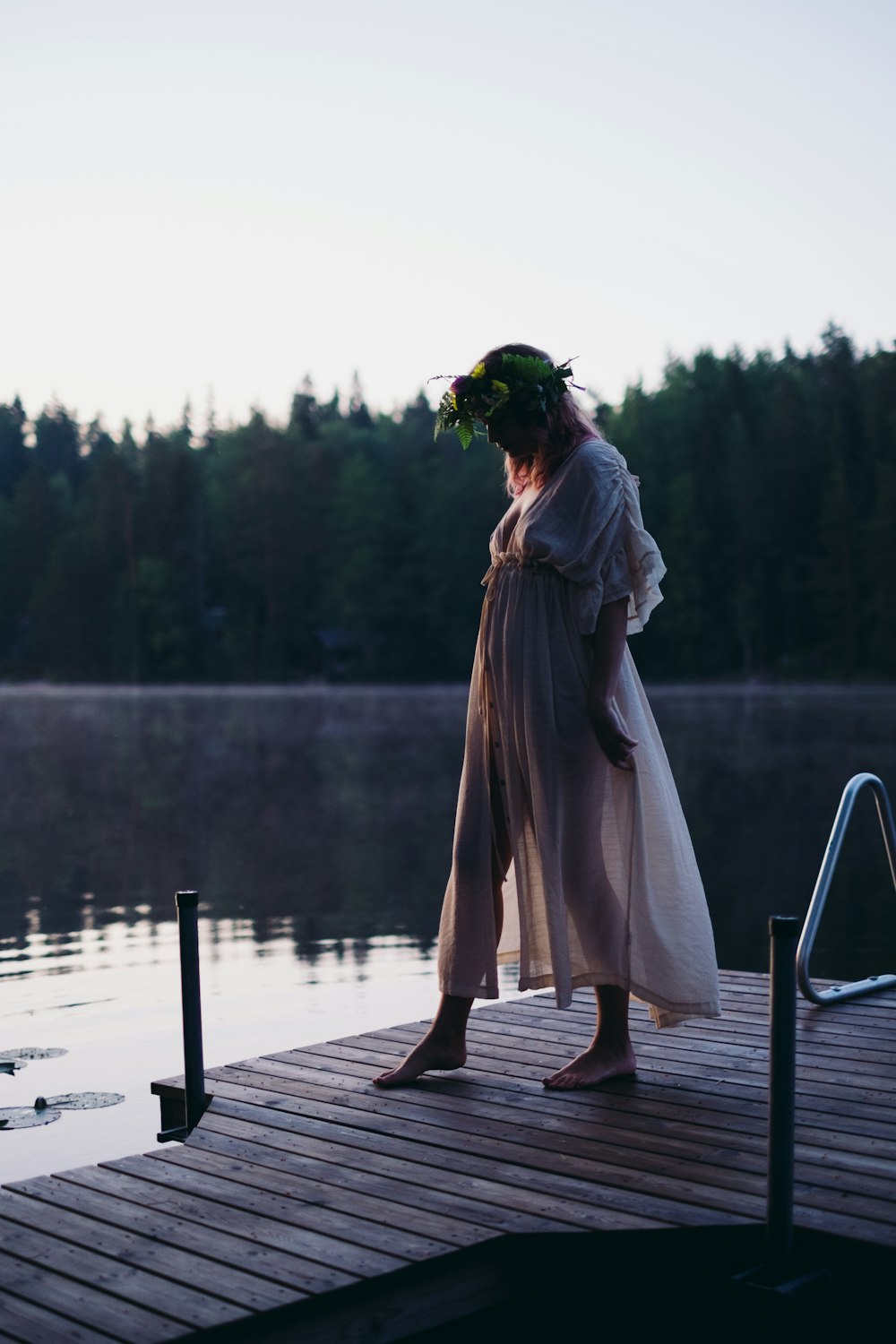 a woman standing on a dock next to a body of water