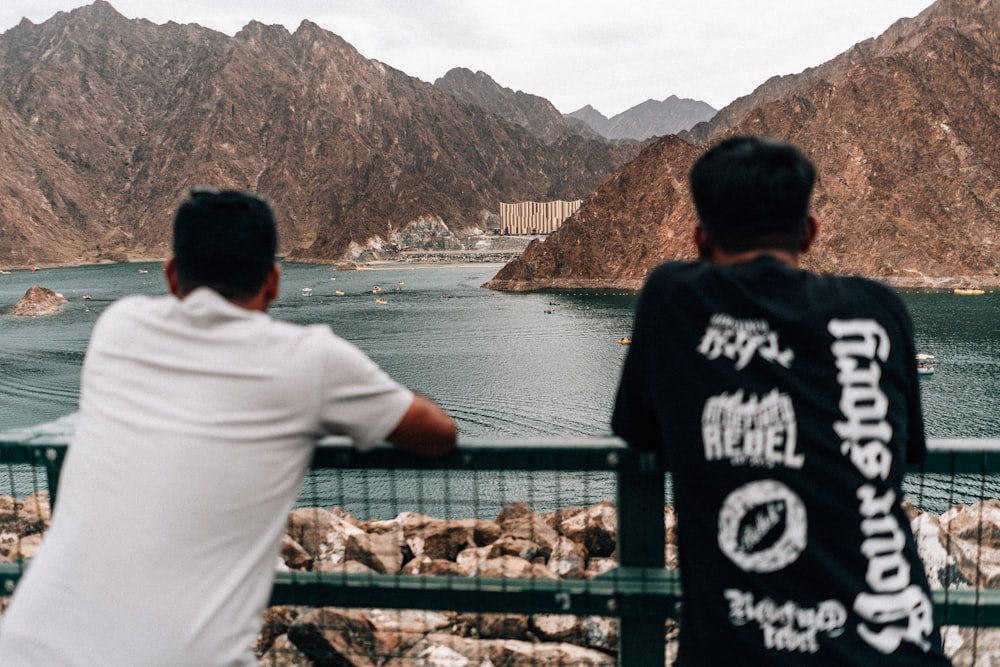 a couple of men standing next to each other near a lake