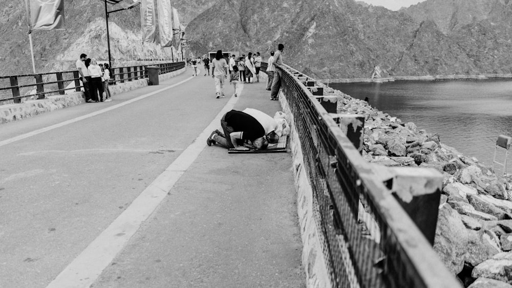 a black and white photo of a man laying on the side of a road