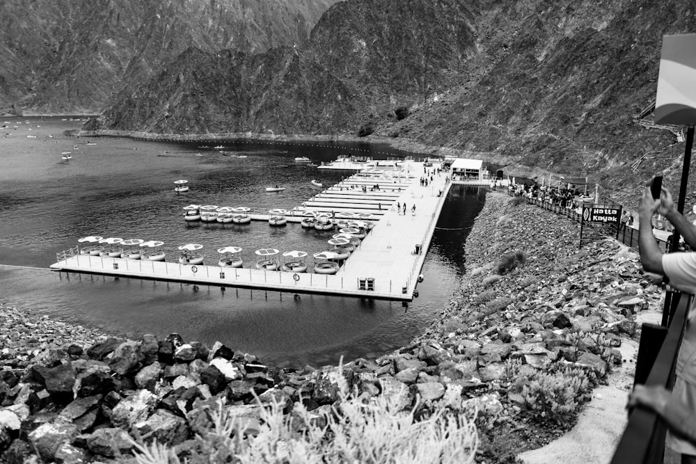 a black and white photo of a pier and mountains