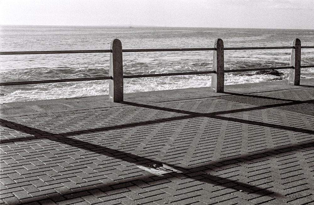 a black and white photo of a bench near the ocean