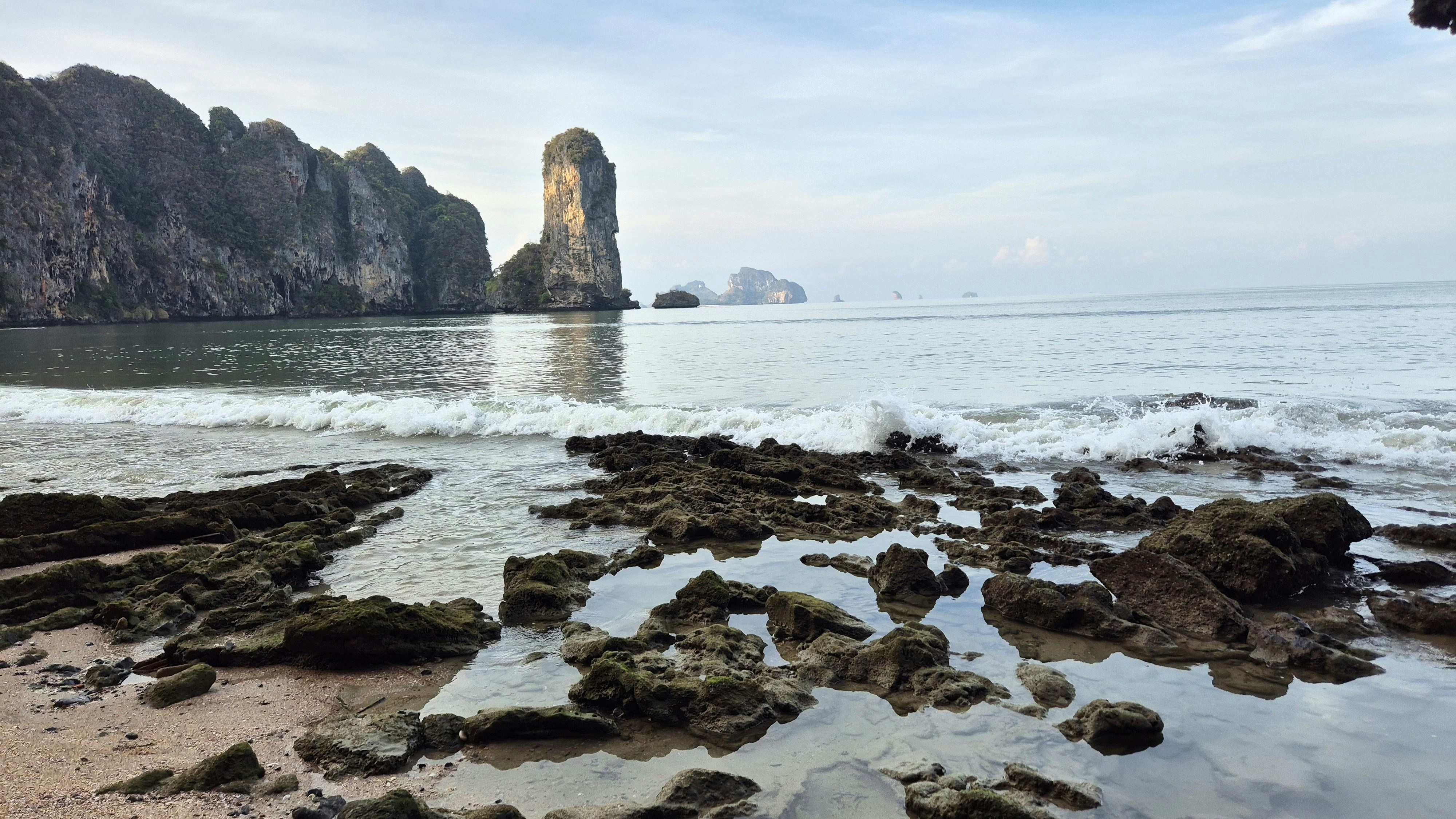 a rocky beach with a rock formation in the background