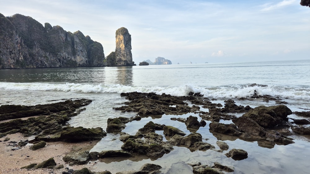 a rocky beach with a rock formation in the background