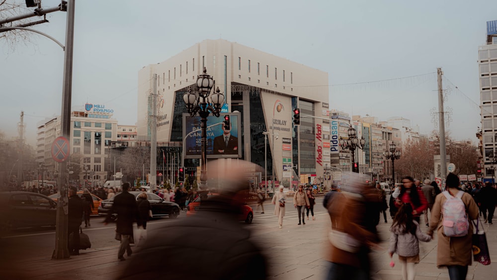 a crowd of people walking down a street next to tall buildings