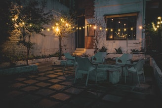 a patio with a table, chairs and lights