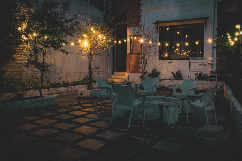 Paver patio at dusk with a lit gas fire feature, ornamental grasses and the Cascade skyline behind a Bend backyard