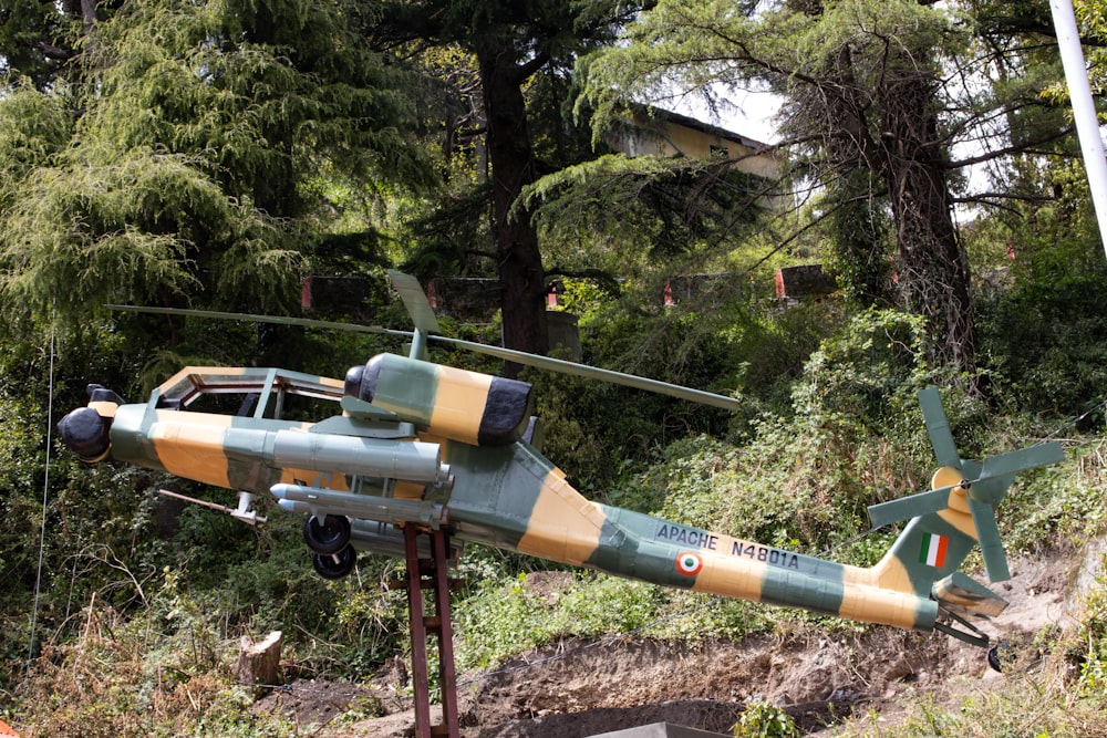 a green and yellow helicopter sitting on top of a hill