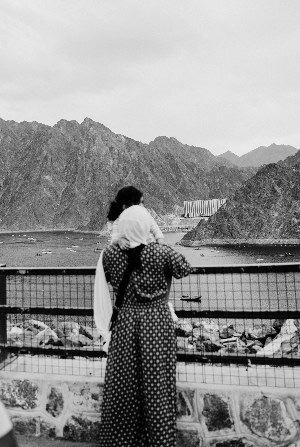 a black and white photo of a woman looking at mountains