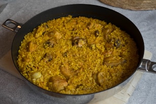 a pan filled with rice and chicken on top of a table