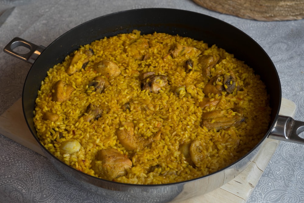 a pan filled with rice and chicken on top of a table