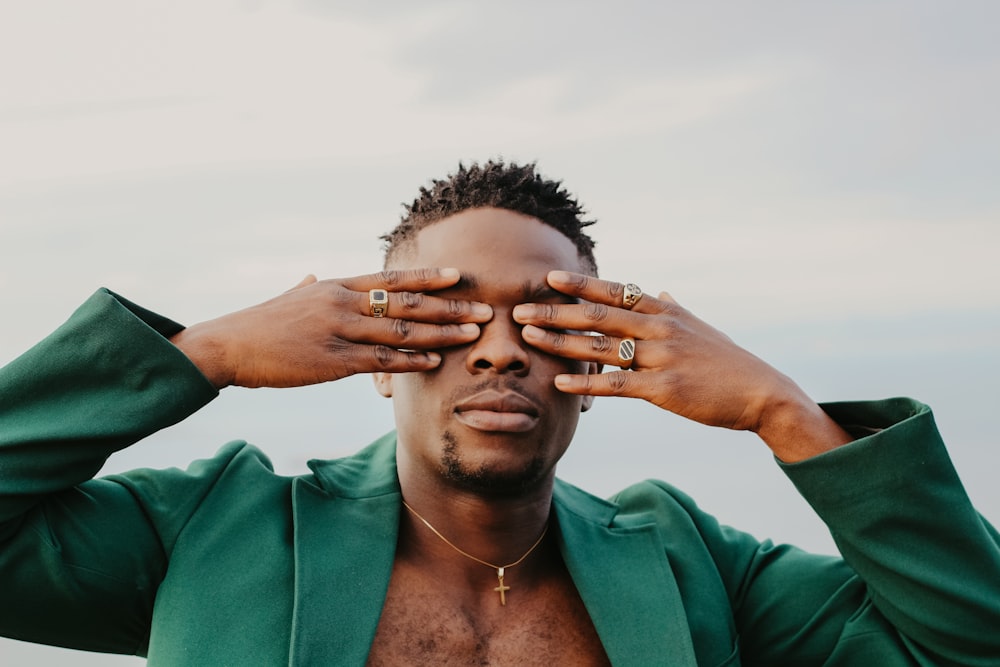 a man in a green jacket covering his eyes