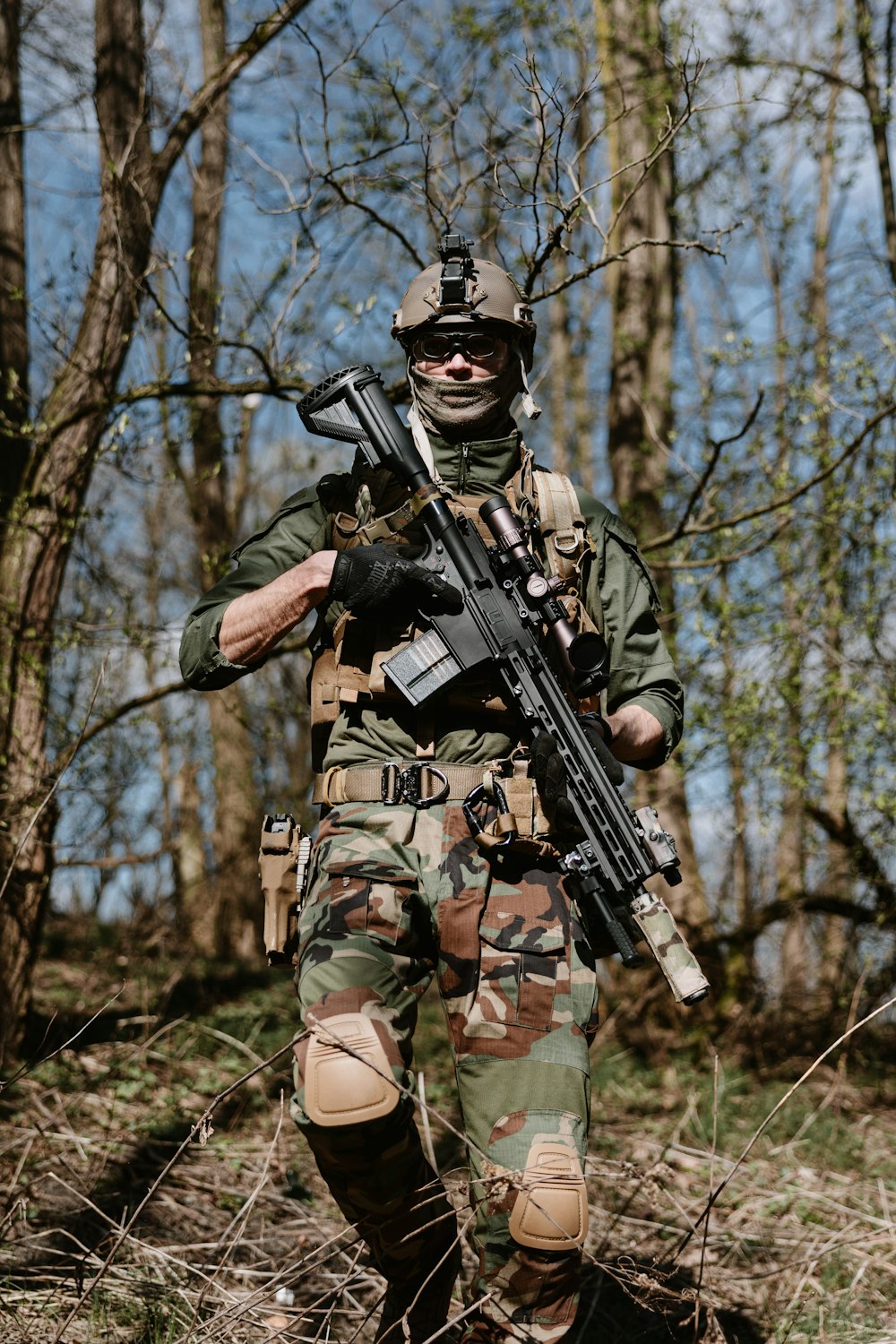 a man in camouflage holding a rifle in the woods