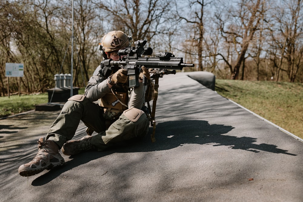a man with a rifle sitting on the ground