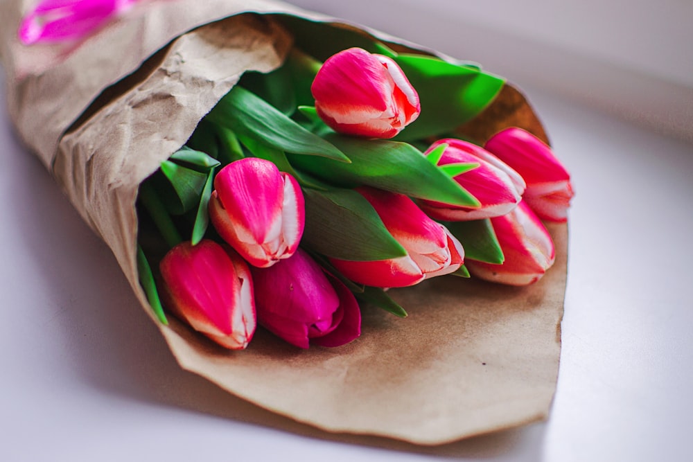 a bouquet of pink tulips wrapped in brown paper