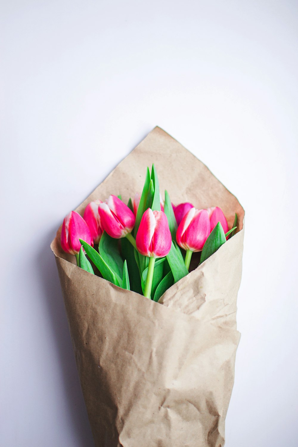 a brown paper bag filled with pink flowers