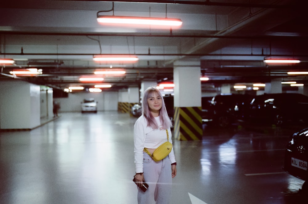 a woman standing in a parking garage holding a yellow purse