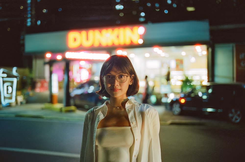 a woman standing in front of a dunkin'donuts store