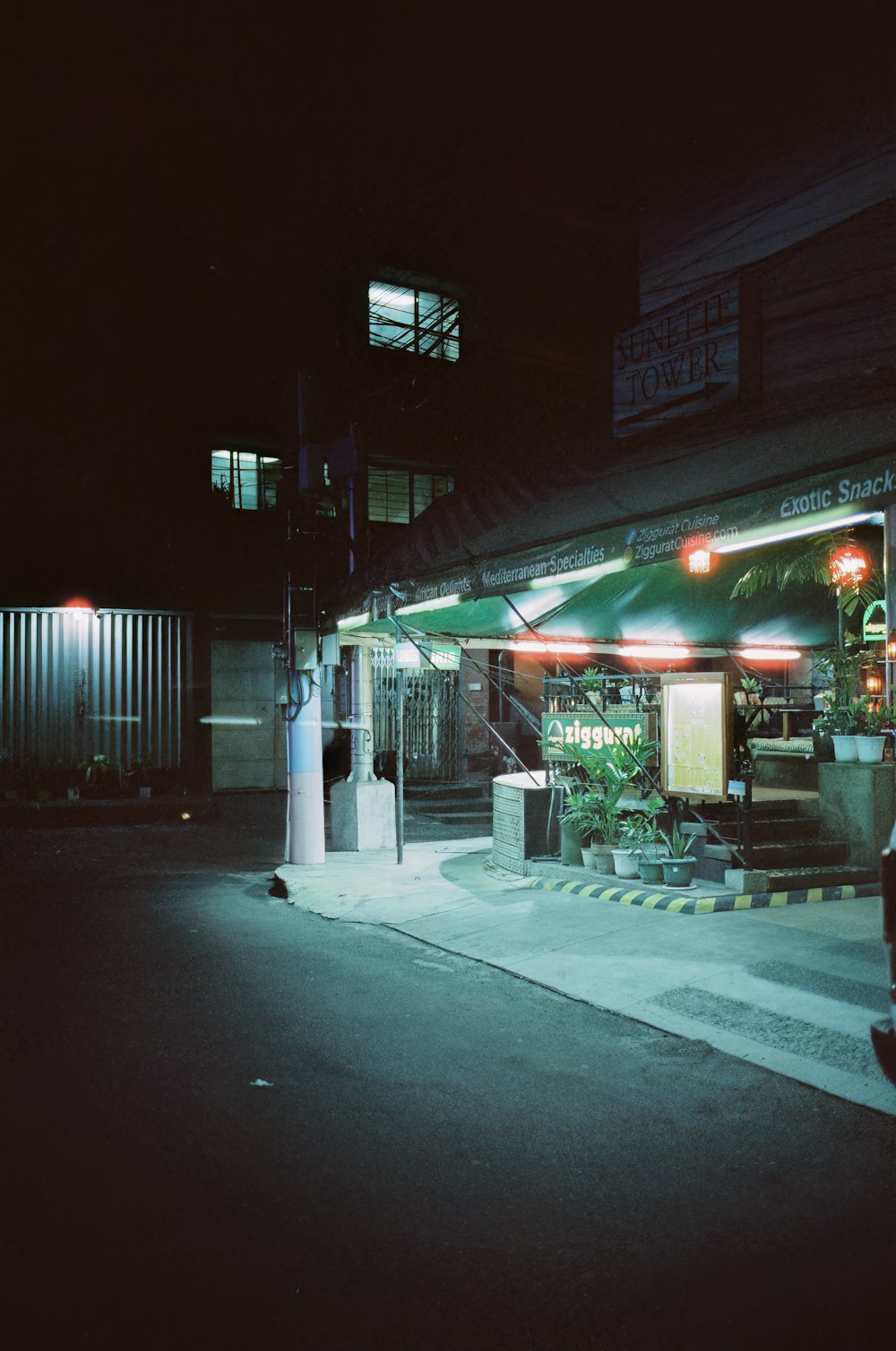 a dark street at night with a restaurant lit up