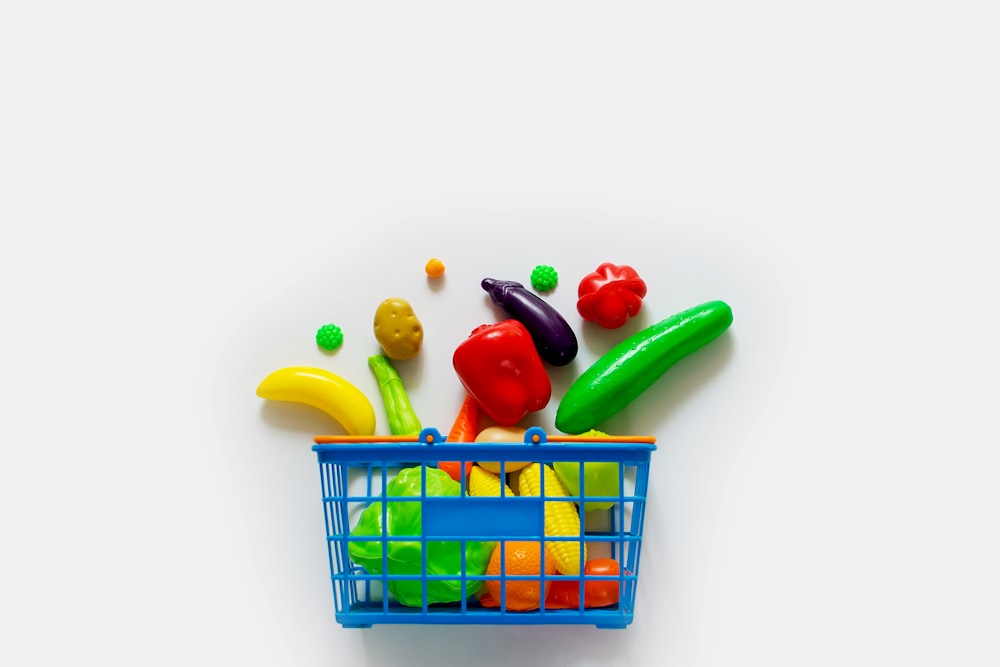 a toy shopping basket filled with lots of colorful toys