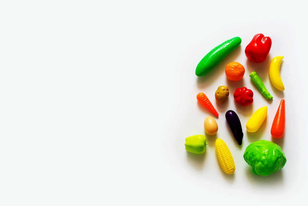 a group of plastic fruits and vegetables on a white surface