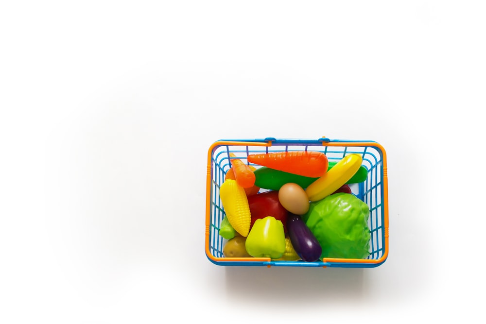 a basket of assorted fruits and vegetables on a white background