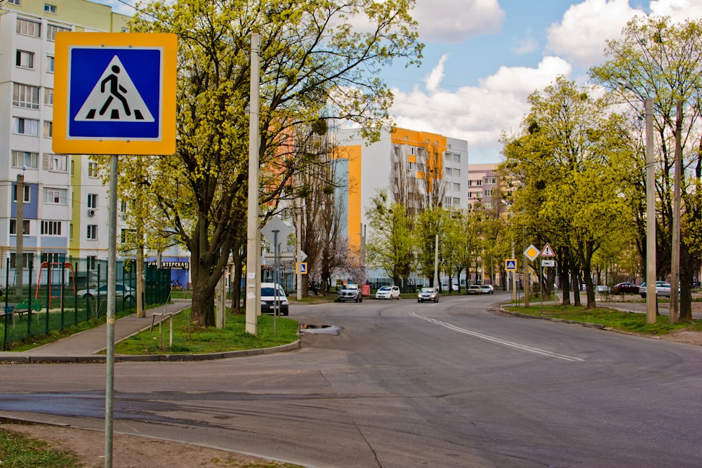 a blue and yellow street sign sitting on the side of a road