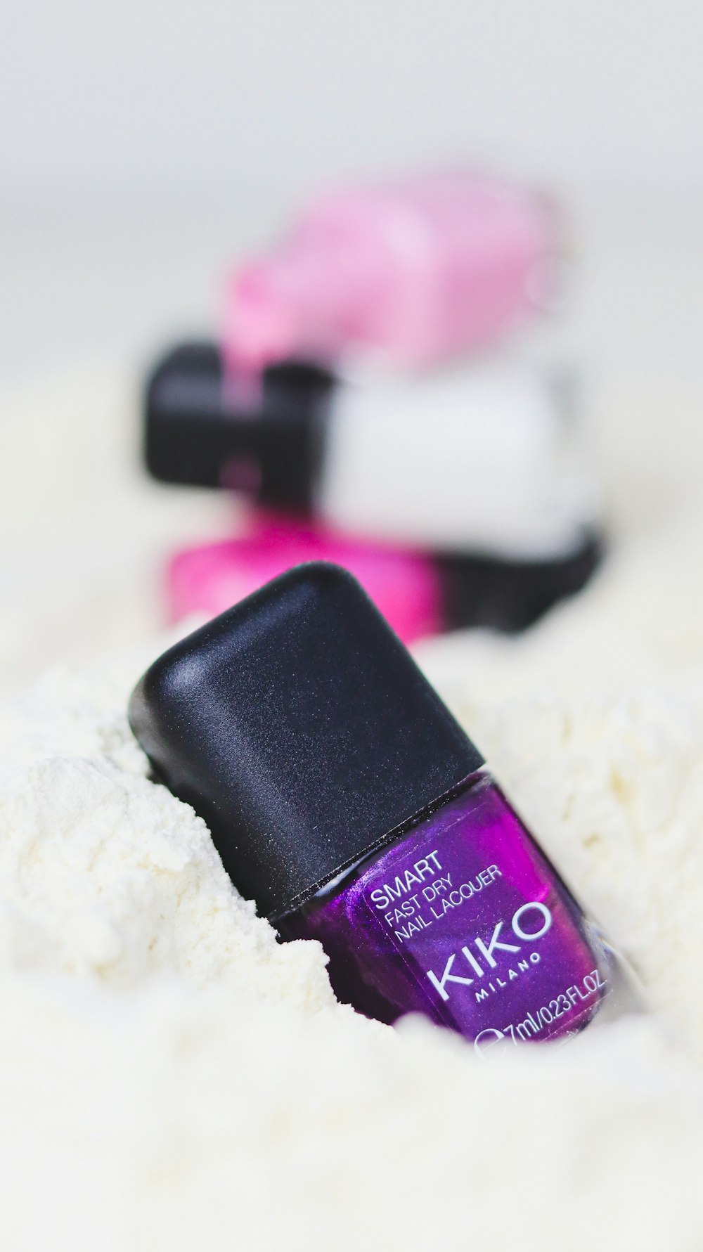 a purple nail polish sitting on top of a white surface