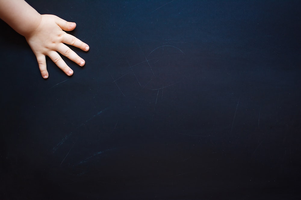 a baby's hand on top of a black surface